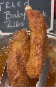 two fried chicken sticks are in a bowl with sauce and a sign that says fried baby kids