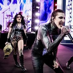 three women in leather outfits on stage with one holding a microphone and the other singing