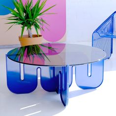 a glass table with blue legs and a potted plant on top