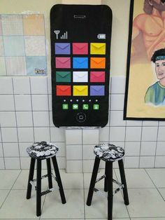 two small stools in front of a cell phone with an image on the wall behind them