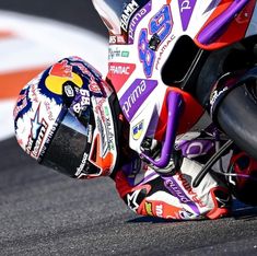 a person riding on the back of a motorcycle down a race track with it's helmet up