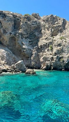 the water is crystal blue and clear with some rocks on it's sides in front of a rocky cliff