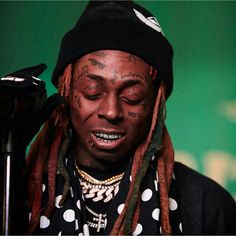 a man with dreadlocks on his head and wearing a black hat is holding a microphone