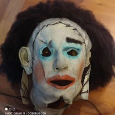 a white mask with black hair and blue eyes