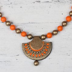 an orange and gold necklace on a white surface