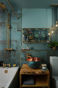 A bold bathroom that has golden brassware, hanging ceiling lights, added greenery and neutral tones to create a luxury ambiance of relaxation. Bathroom Decor Gray, Bathroom Without Windows, Bathroom Floating Shelves, Teal And Copper, Western Bathroom Decor, Moody Bathroom, Western Bathroom, Bathroom Pink, Small Shower