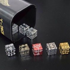 several different colored dices sitting next to each other on a black surface with gold lettering