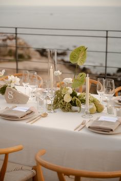 the table is set with flowers and candles for an elegant wedding reception overlooking the ocean