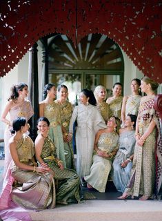 a group of women standing next to each other in front of a building with red and gold decorations