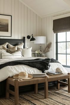 a bedroom with white walls and black furniture, including a large bed in the center