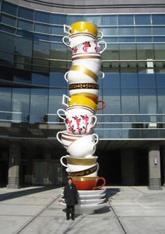 a man standing in front of a tall stack of coffee cups on top of each other