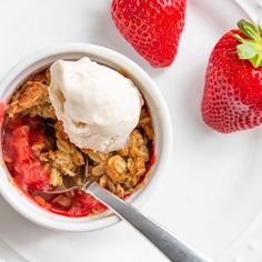 a bowl of granola with ice cream and strawberries on the side, ready to be eaten