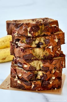 chocolate chip banana bread stacked on top of each other next to a bunch of bananas