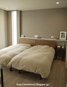 two twin sized beds in a room with wood floors and white walls, one is empty