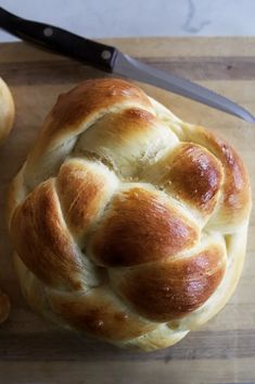 a hot cross bread sitting on top of a wooden cutting board next to a knife