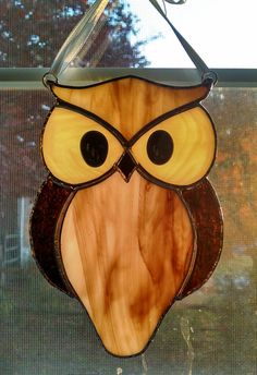 a stained glass owl hanging from a window