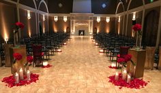 a room filled with lots of chairs covered in red rose petals and votive candles