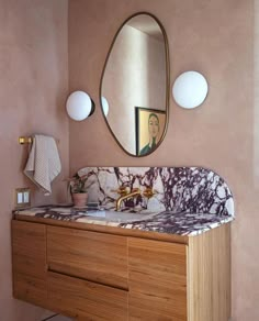 a bathroom vanity with marble counter top and two round mirrors on the wall above it