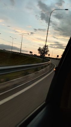 the sun is setting on an empty highway as seen from inside a vehicle's side view mirror