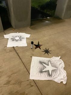 three white t - shirts with black stars on them laying on the ground next to one another