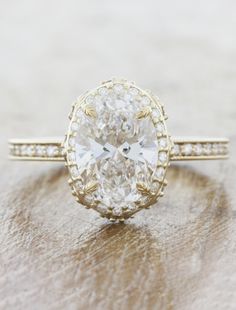 an oval cut diamond ring on top of a wooden surface