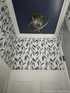 an overhead view of a bathroom with blue and white wallpaper, ceiling fan and light fixture