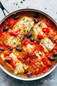 fish with tomatoes, olives and capers in a pan on a table top