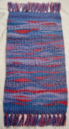 a blue and red rug with fringes on it's end, laying on a white surface