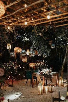 an outdoor dining area with candles and flowers on the table, surrounded by greenery