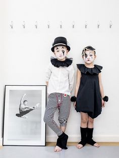 two children dressed up as clowns standing in front of a black and white photo