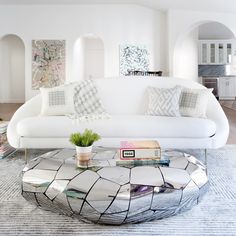 a living room filled with white furniture and lots of books on top of a coffee table