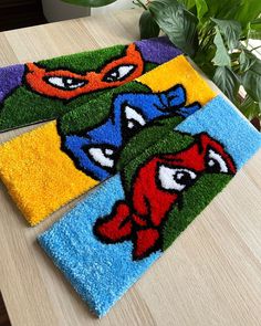 three bathroom rugs with ninja turtles on them sitting on a table next to a potted plant