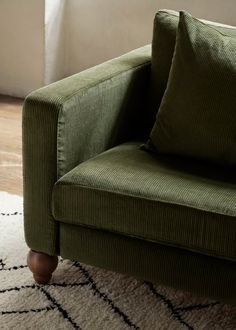 a green couch sitting on top of a white rug