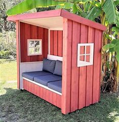 a small red and white shed with a blue couch in the corner next to it