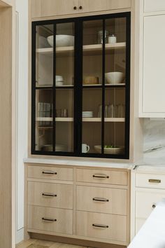 a kitchen with white cabinets and black glass doors