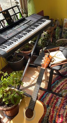 a guitar sitting on top of a wooden floor next to a keyboard and potted plant