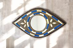 a mirror that is on the wall with blue and gold designs around it's edges