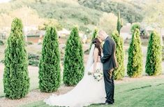 a bride and groom kissing in front of some trees