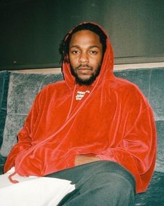 a man in a red hoodie sitting on a couch