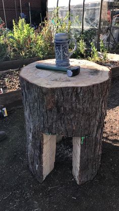 a tree stump with a vase sitting on it's side table in a garden