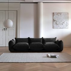 a black couch sitting on top of a wooden floor next to a white rug in a living room