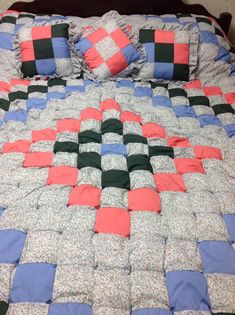 a bed with two pillows on top of it and a checkerboard quilt in the middle