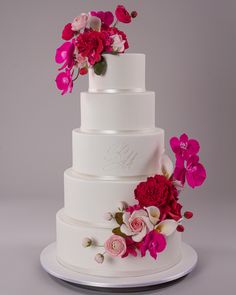 a white wedding cake with pink and red flowers