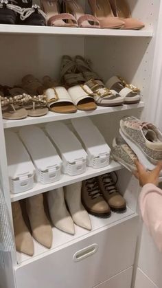 a woman is looking at shoes on shelves in a shoe closet with white bins