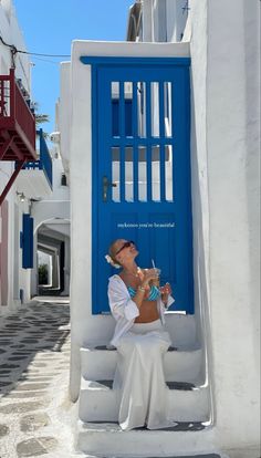 a woman sitting on steps in front of a blue door