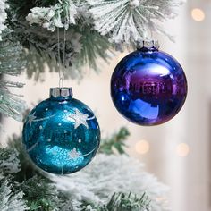 two blue and purple ornaments hanging from a christmas tree