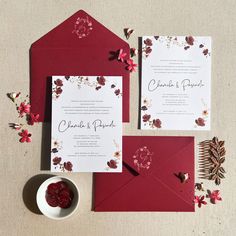 the wedding stationery is set up with red envelopes and matching cards, along with a small bowl of raspberries