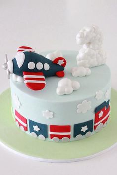 a birthday cake decorated with an airplane and clouds on the top is blue, white, and red