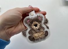 a person holding a small stuffed animal keychain