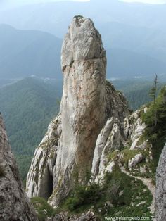 a rock formation on top of a mountain in the middle of some trees and mountains